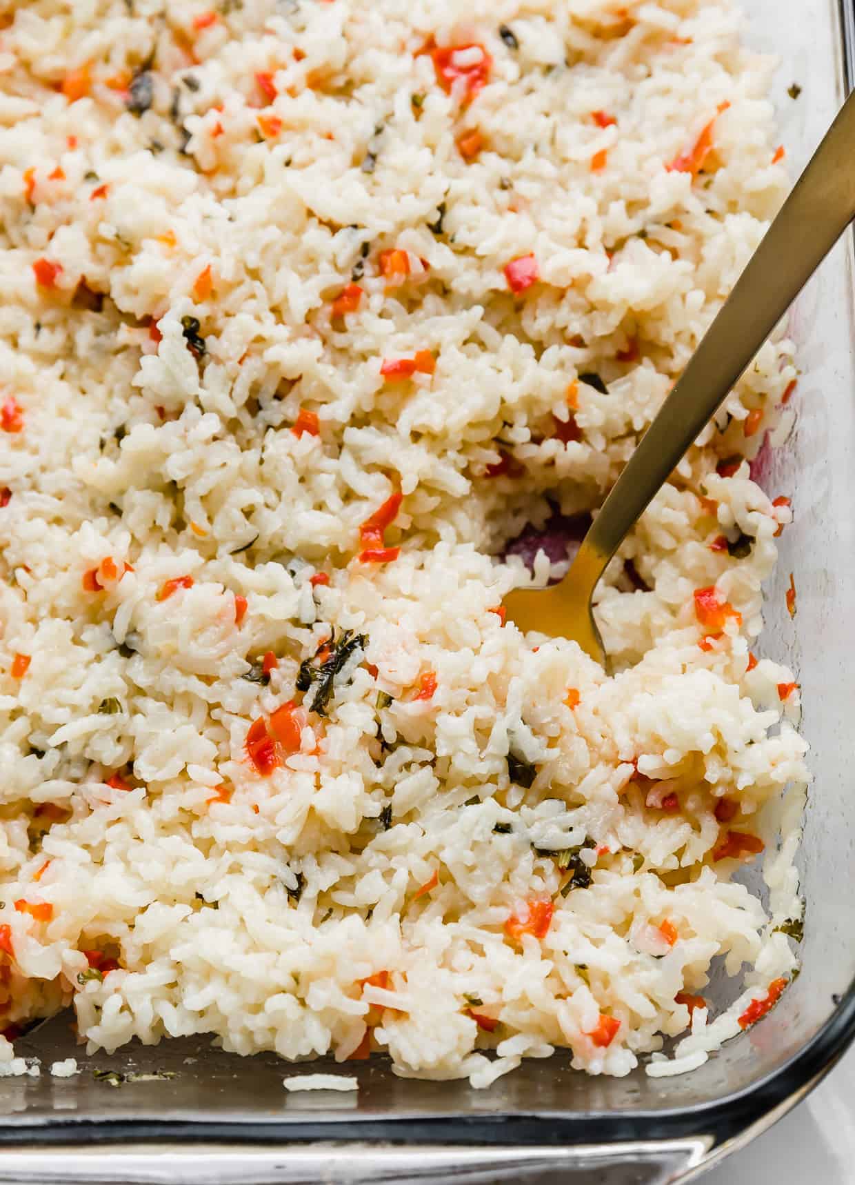 A gold spoon in a pile of red pepper studded Sweet Pepper Rice.