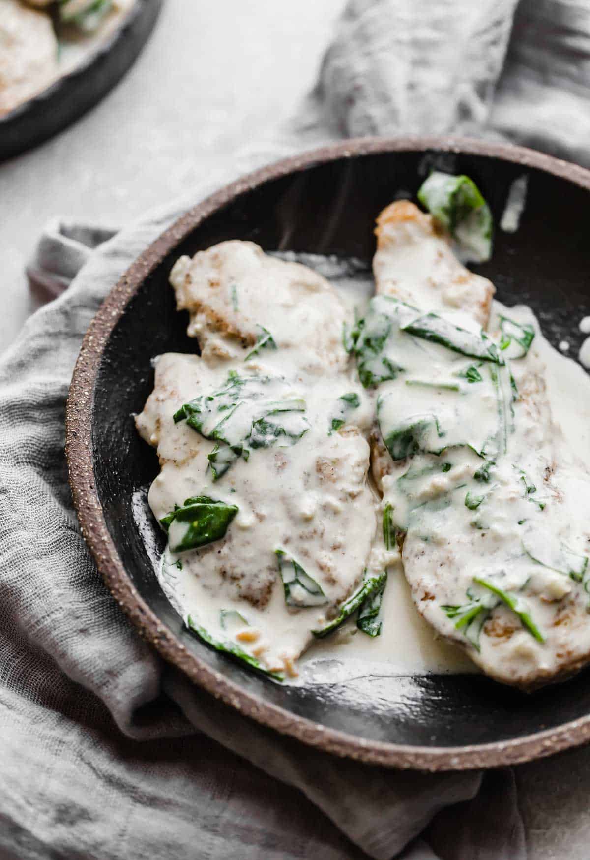 A creamy mustard chicken breast on a black plate.