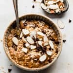 A bowl with almond joy oatmeal topped with coconut, almonds, and chocolate chips.