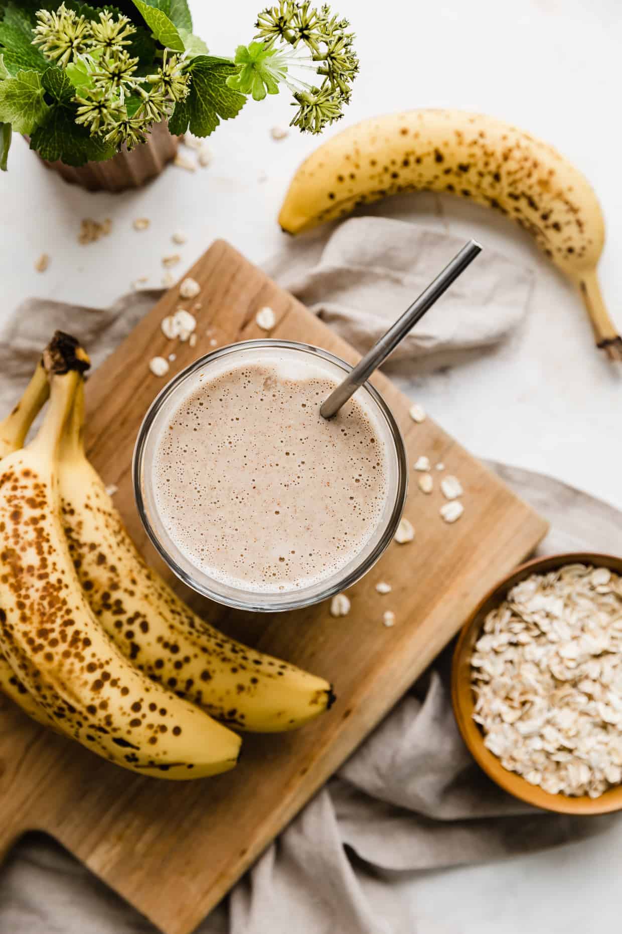 Overhead photo of a Lactation Smoothie on a wooden board with bananas around. 