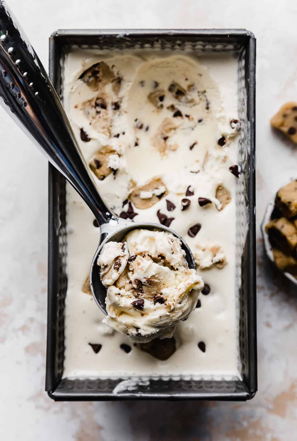 An ice cream scoop with a large scoop of Chocolate Chip Cookie Dough Ice Cream in it. 