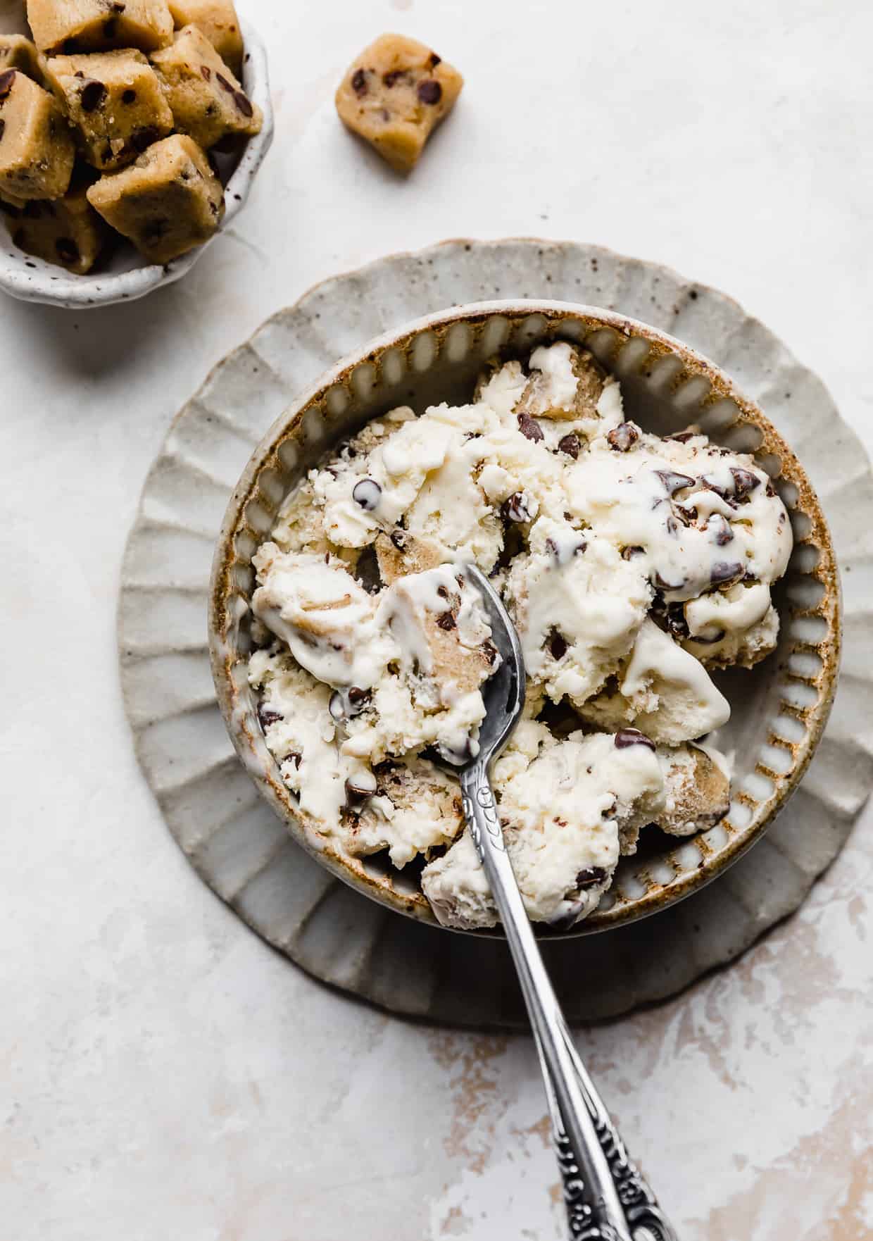 A tan bowl full of cookie dough loaded Chocolate Chip Cookie Dough Ice Cream against a textured white background.