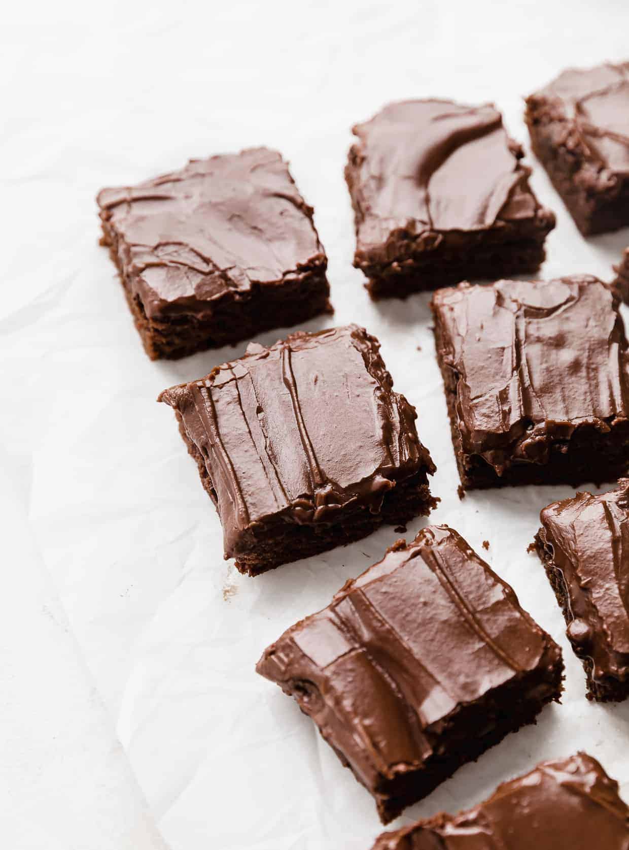 Chocolate frosted lunch lady brownies cut into squares on a white background.