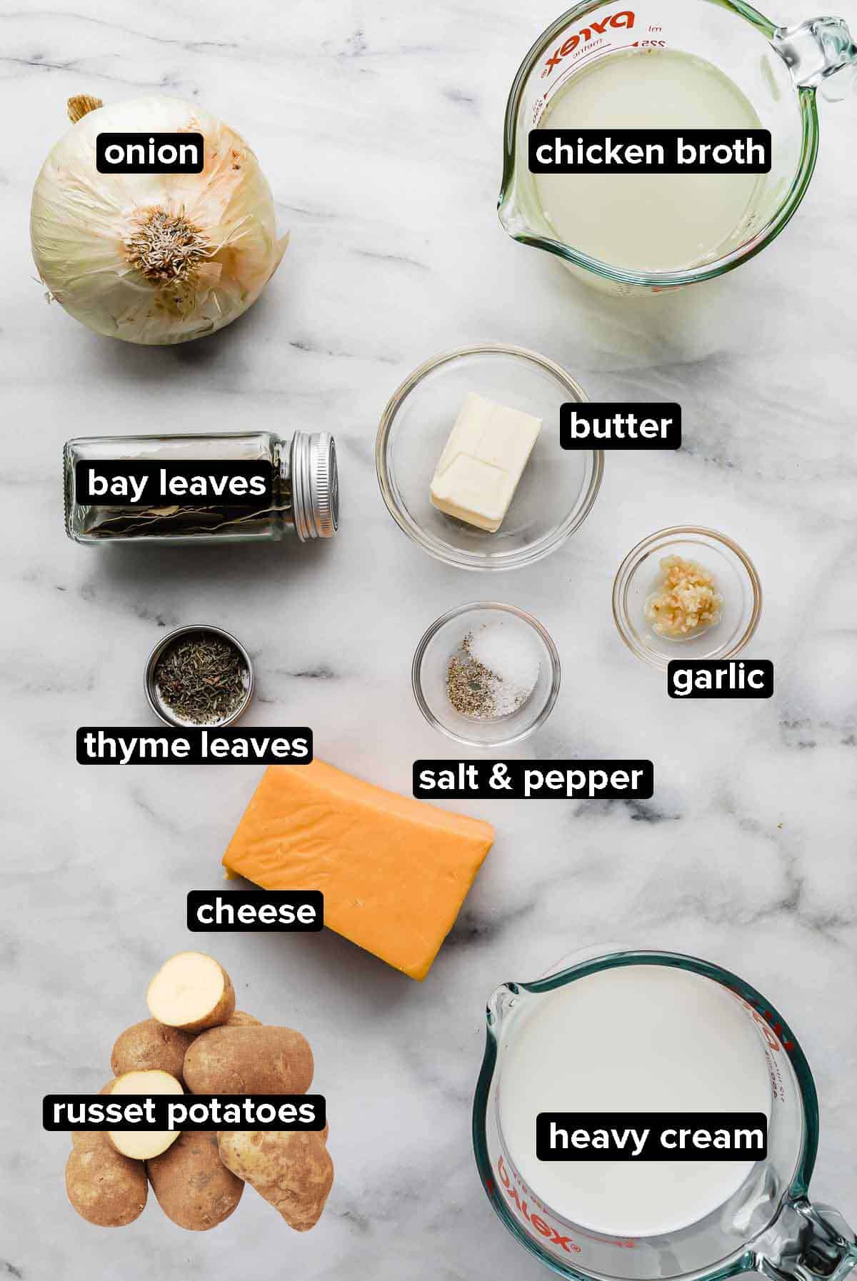 Scalloped potato recipe ingredients portioned into glass bowls on a white and gray marble background.