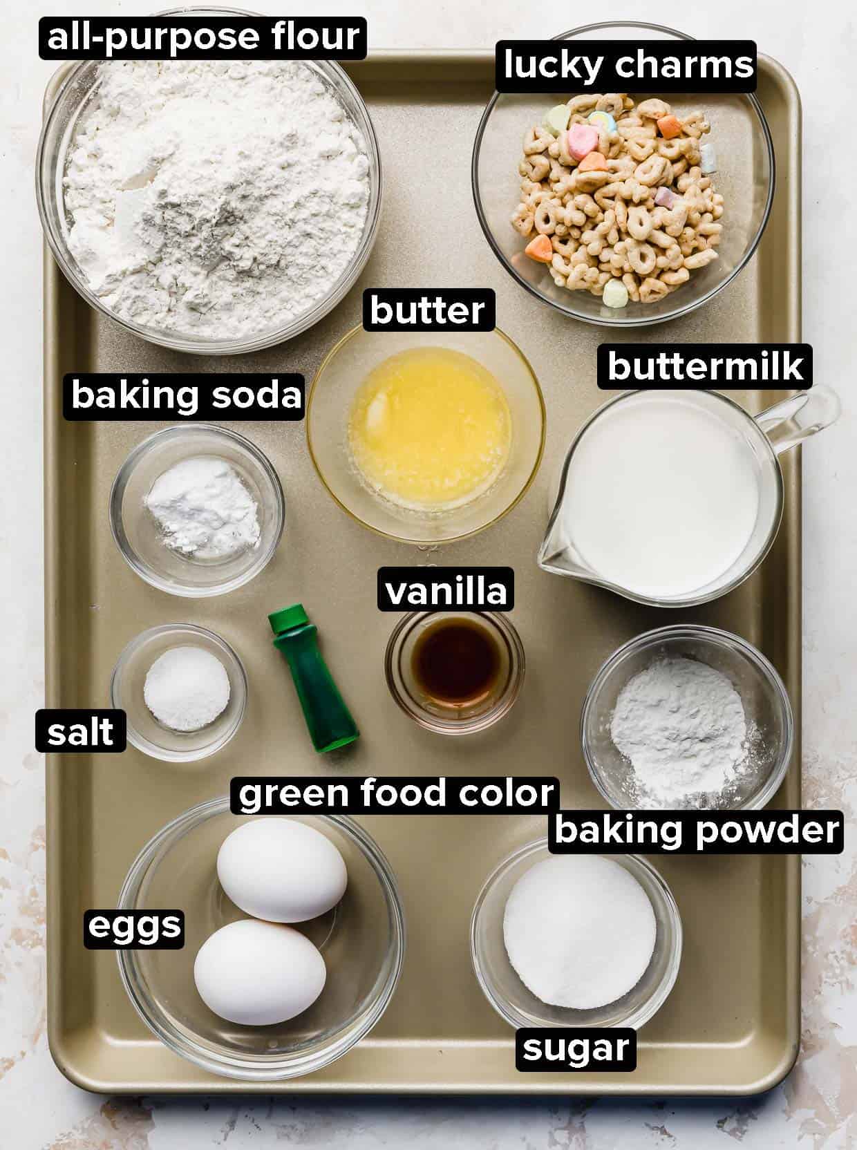 Ingredients used to make green St. Patrick's Day Pancakes portioned into glass bowls on a bronze baking sheet.