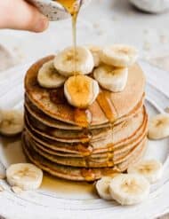 A stack of Banana Oatmeal Pancakes topped with sliced bananas.