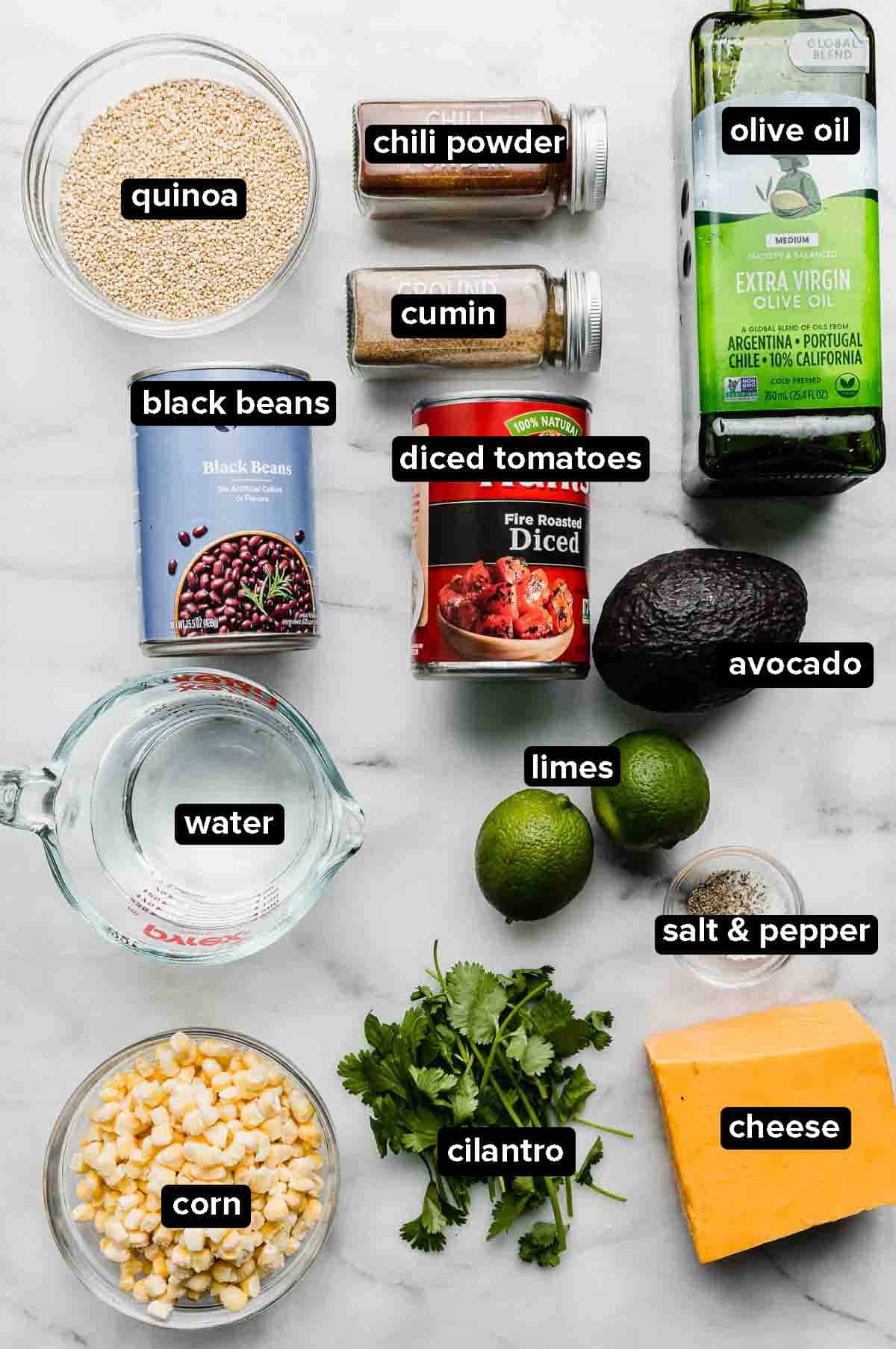 Mexican Quinoa ingredients on a white background: cheese, cilantro, corn, quinoa, spices, olive oil, black beans, limes, avocado.