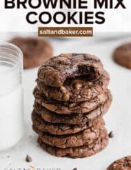 A stack of brownie mix cookies on a white background next to a glass of milk.