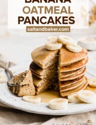 A stack of golden brown banana oatmeal pancakes on a white plate with a sliver of pancakes cut out from the stack.
