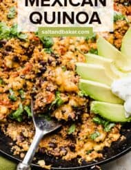 A serving spoon scooping into a Mexican quinoa skillet dish that has been topped with sliced avocado and sour cream.
