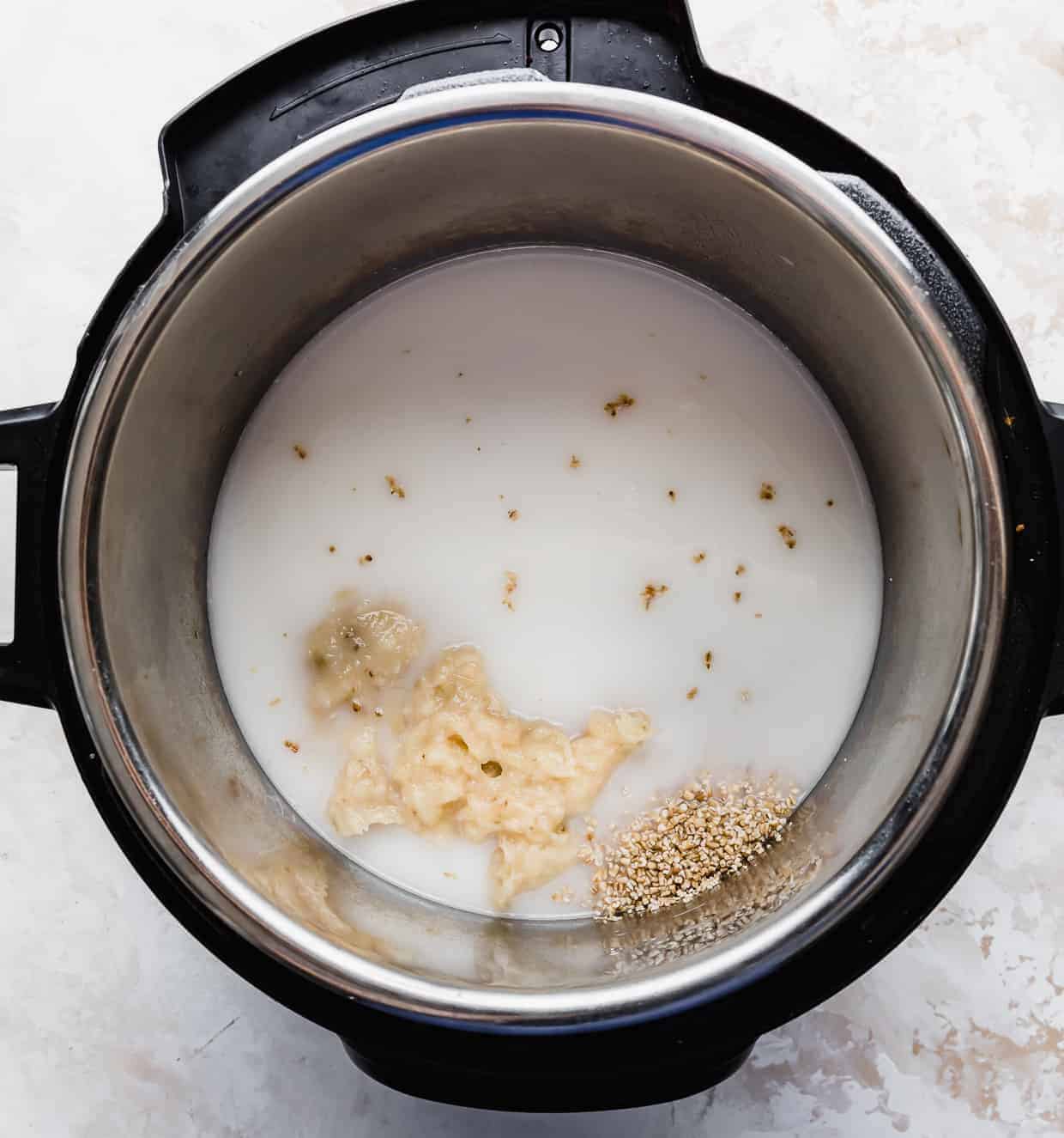 An instant pot full of almond milk, water, mashed bananas, and steel cut oats.