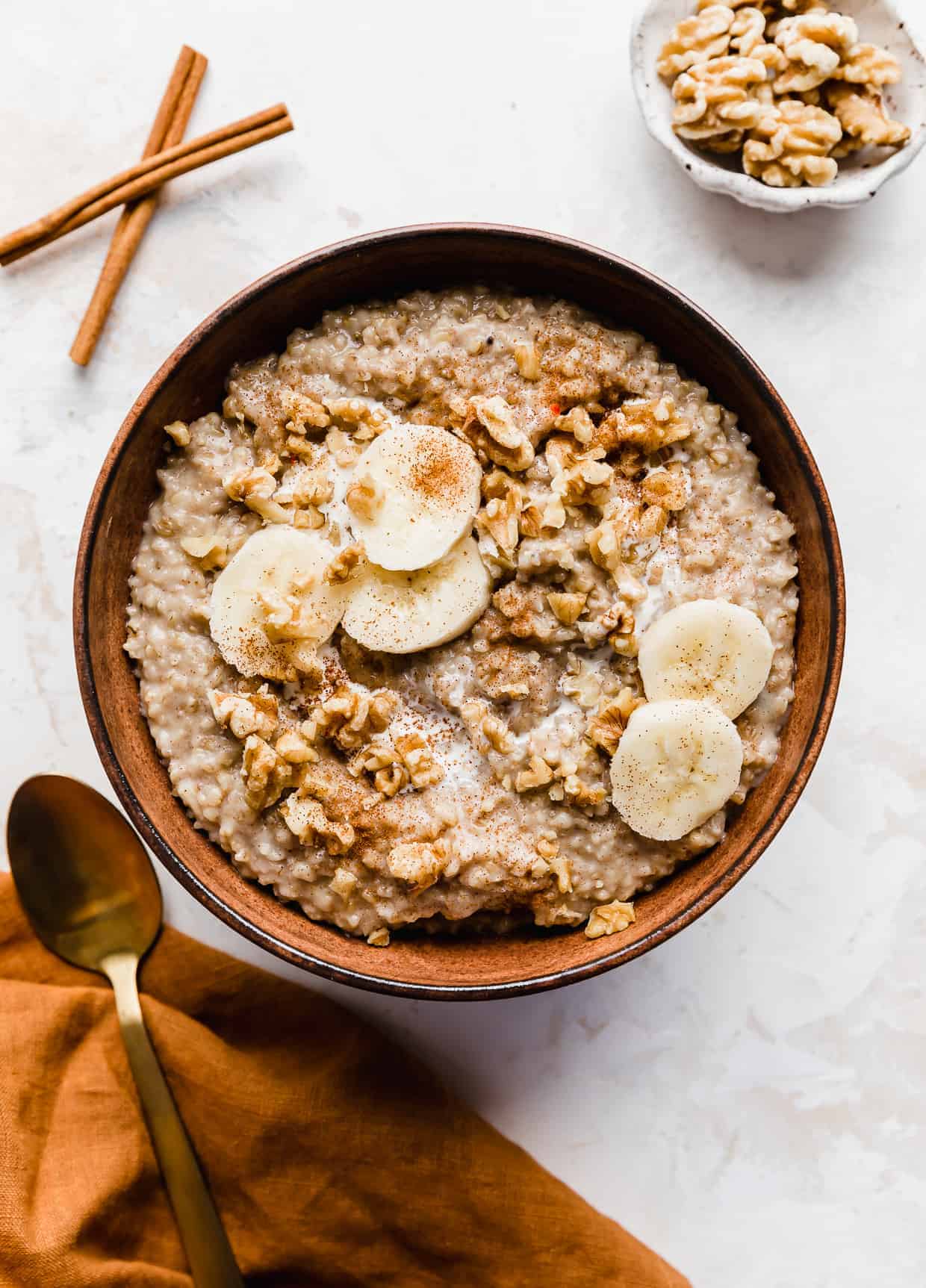 A bowl of Banana Steel Cut Oats against a white textured background. 