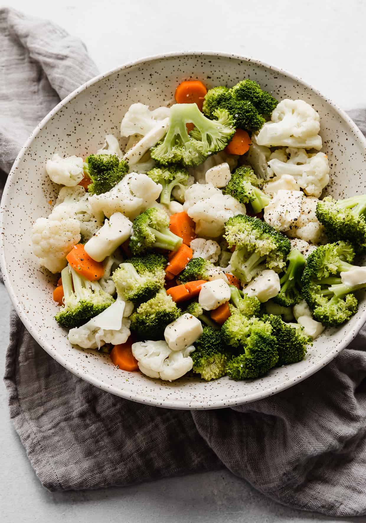 Buttered Vegetables in a large serving bowl with cubes of butter over the top.