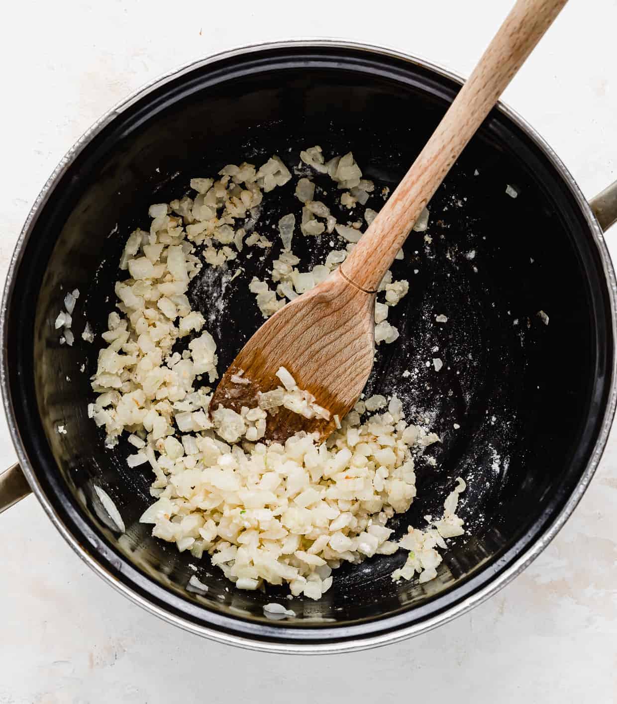 Diced onion mixed with flour in a black pot.