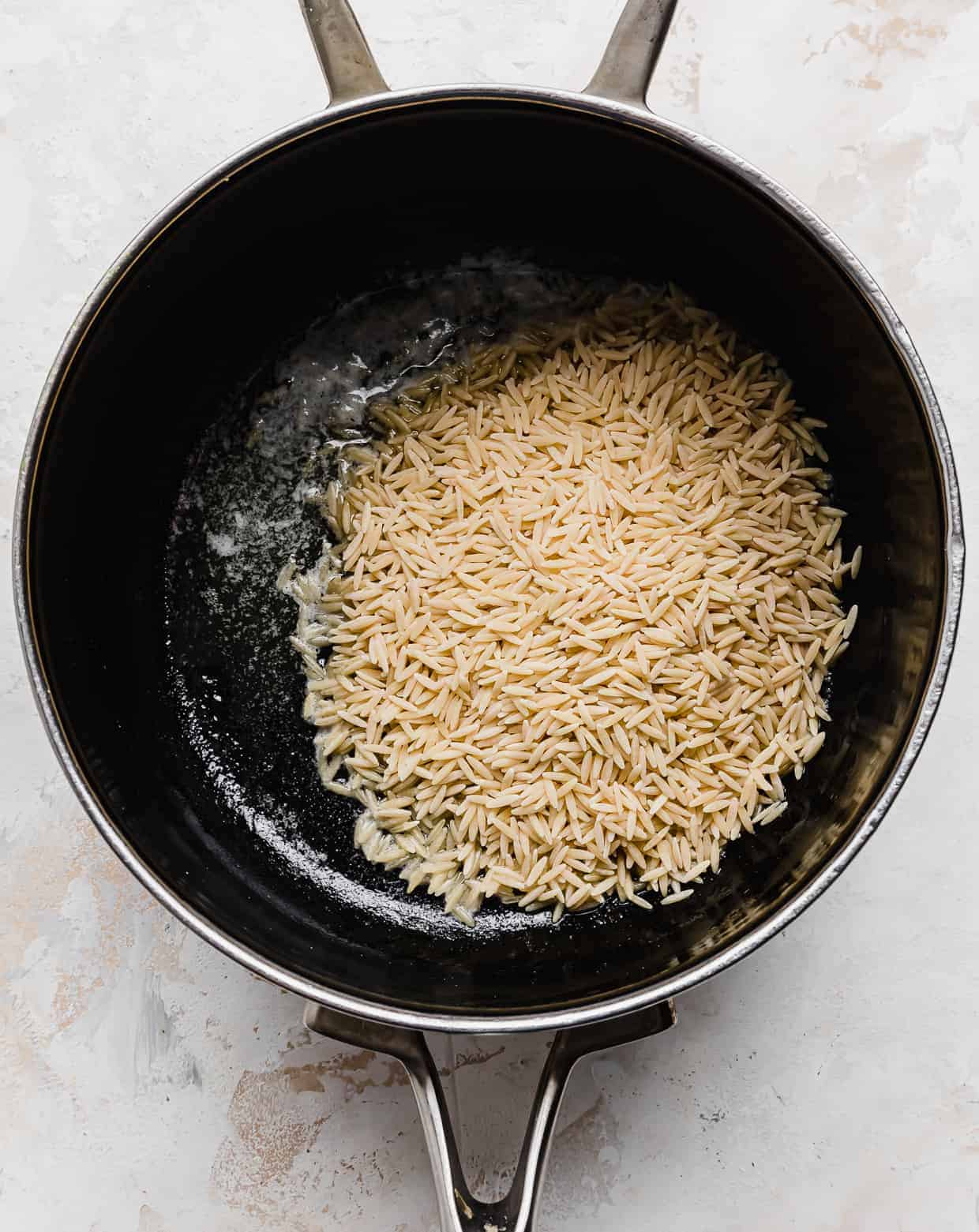 Orzo pasta in a black saucepan.
