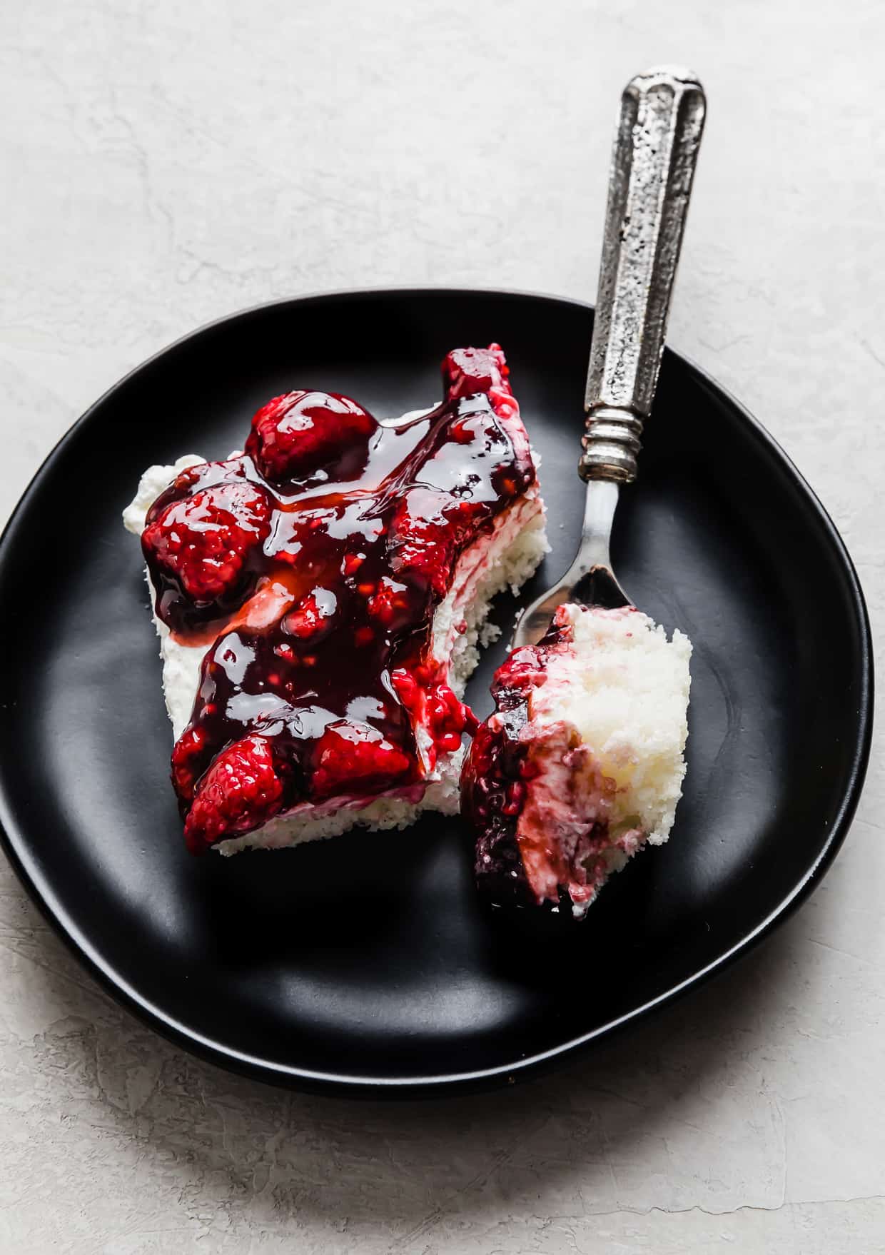 A slice of Raspberry Shortcake Sheet Cake on a black plate.