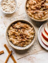 A bowl of Apple Cinnamon Oatmeal topped with chopped pecans and cinnamon.