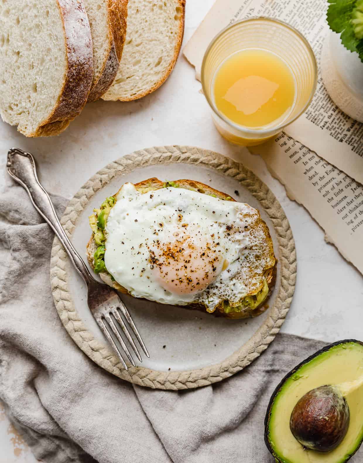 A slice of bread with smashed avocado and a cooked egg on it. 