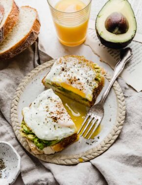 A slice of toasted bread with smashed avocado and egg on it.
