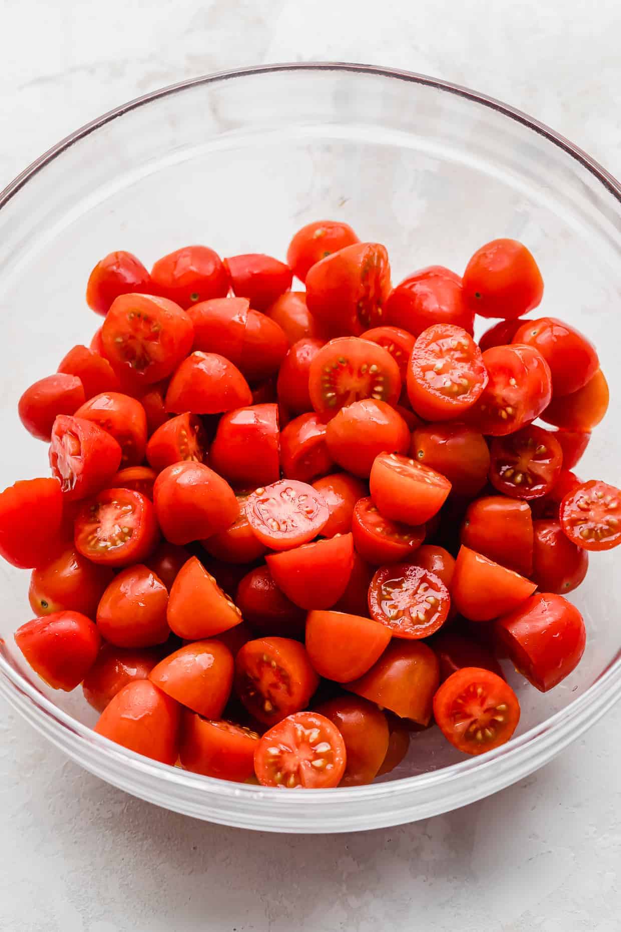 Red Cherry tomatoes cut in half, in a glass bowl. 