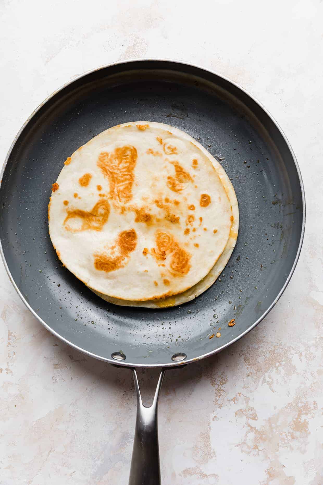 A crispy golden cheese quesadilla in a frying pan.