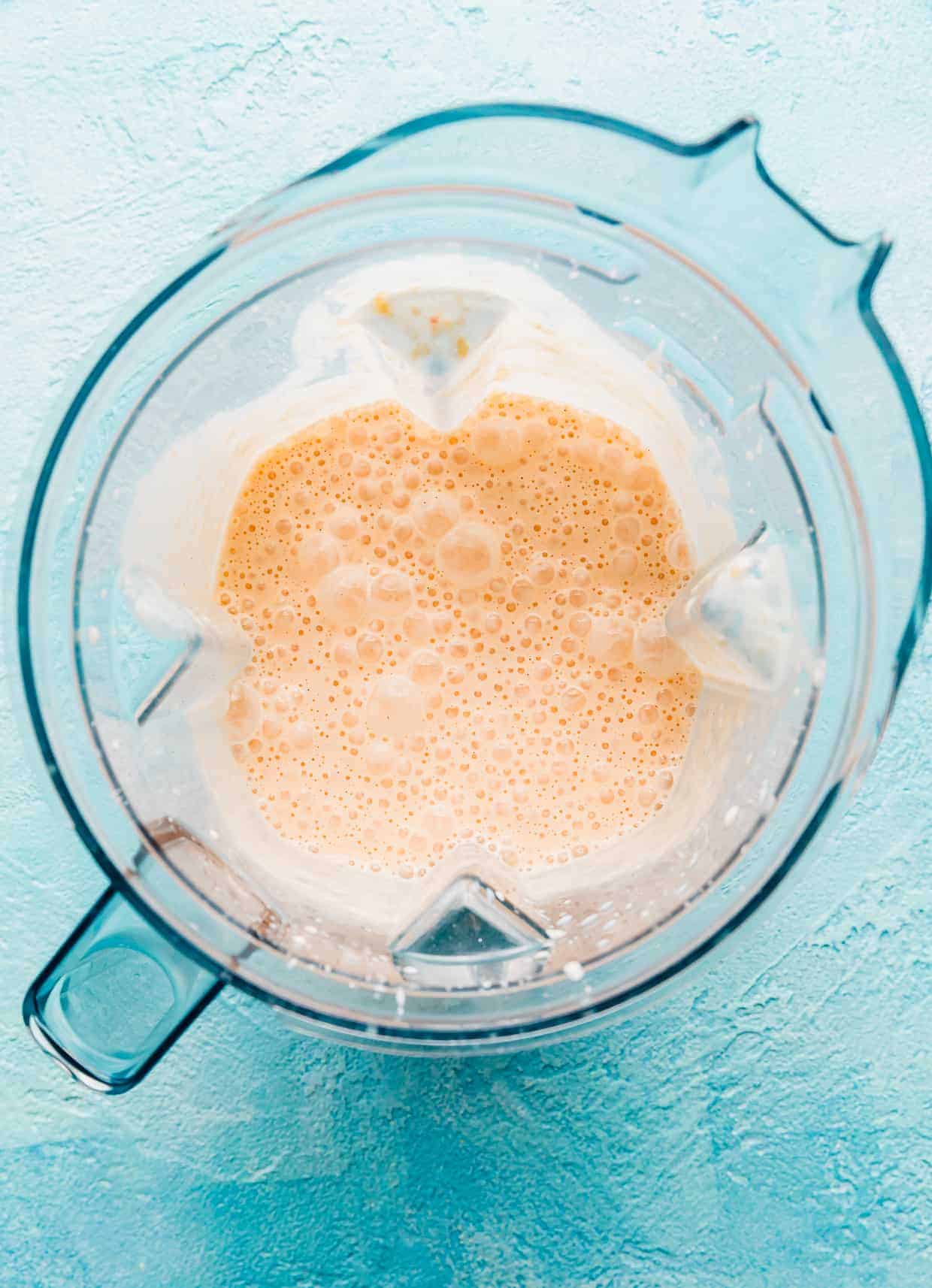 A blended peach milkshake in a blender.