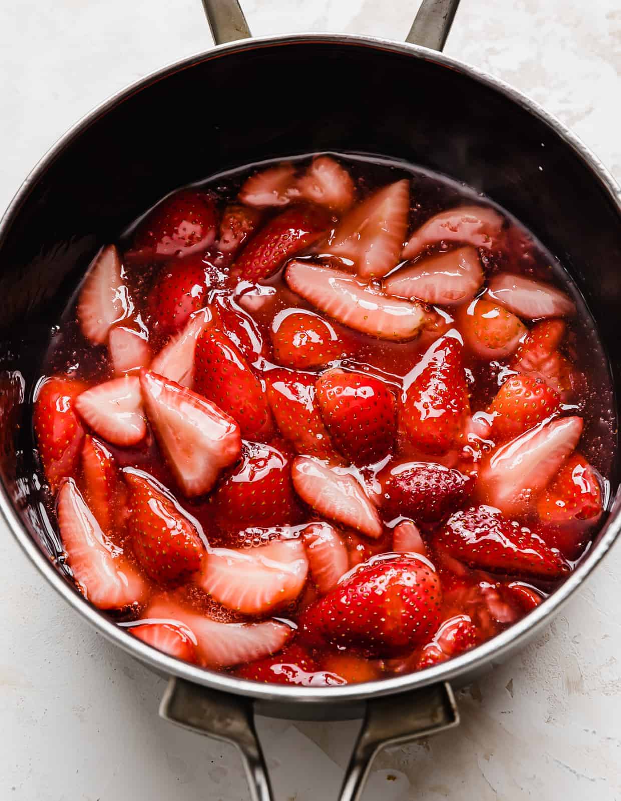 A homemade fresh strawberry sauce for Strawberry Shortcake Trifle in a black saucepan.