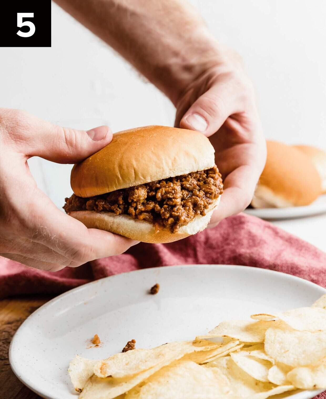 Two hands holding up a Homemade Sloppy Joe.