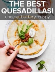 A cheese quesadilla topped with avocado, salsa, and sour cream.