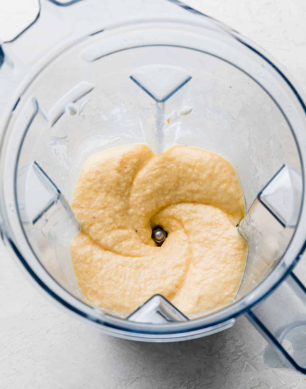 A banana peach smoothie mixture pureed in a blender.