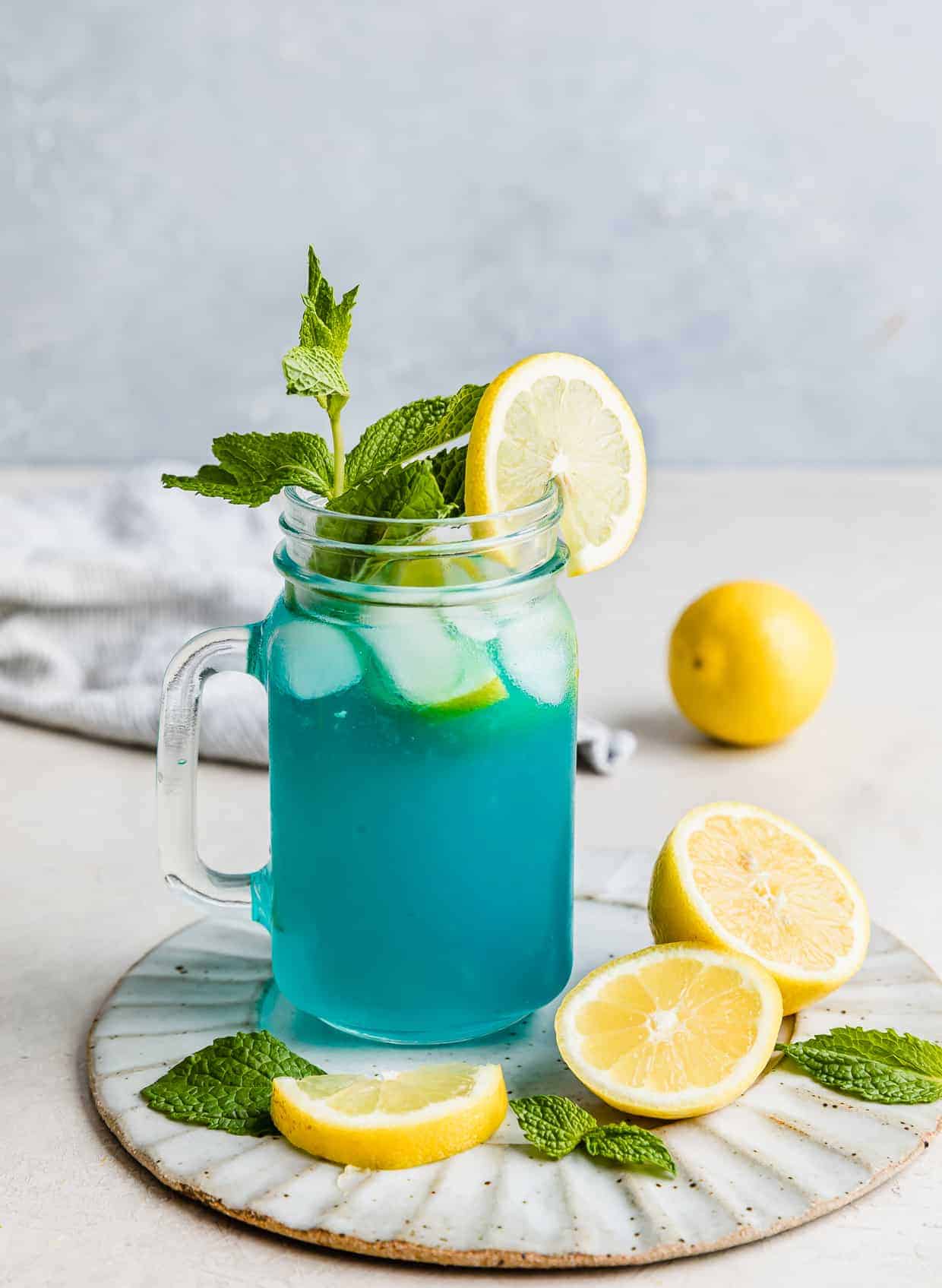 Blue Raspberry Lemonade in a glass jar garnished with a sprig of mint.