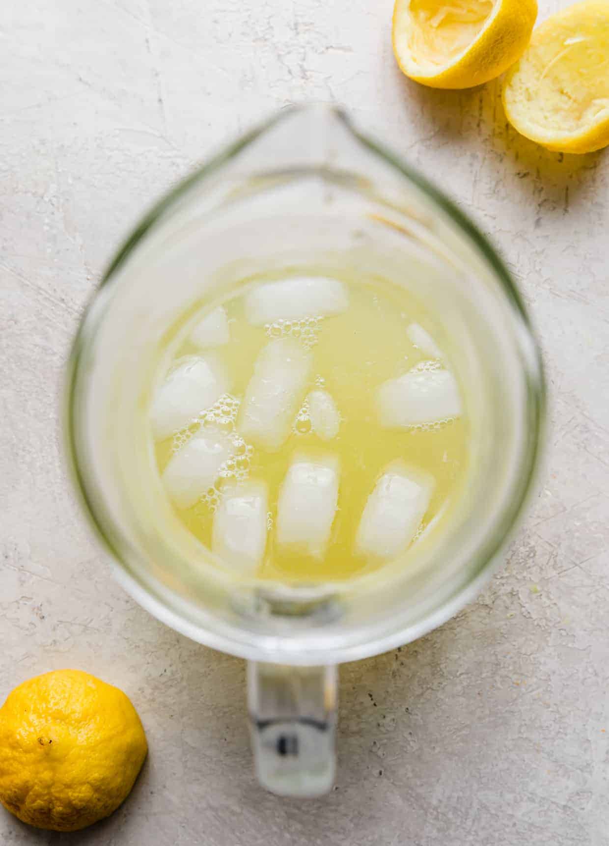 Overhead photo of lemon juice and ice in a glass pitcher.