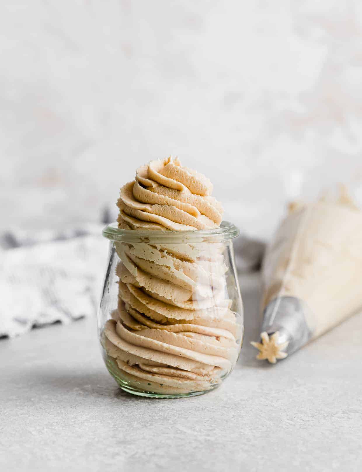 A glass jar with Peanut Butter Frosting piped into the jar using a swirly tip.