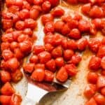 Roasted grape tomatoes on a baking sheet.