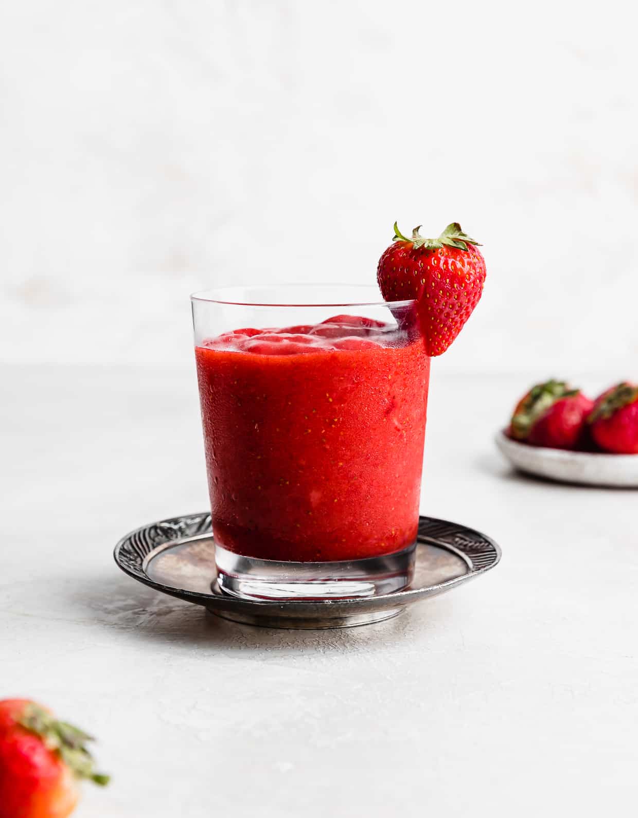 A glass full of Virgin Strawberry Daiquiri on a metal plate.