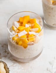 A glass cup full of Mango Overnight Oats topped with fresh diced mango.