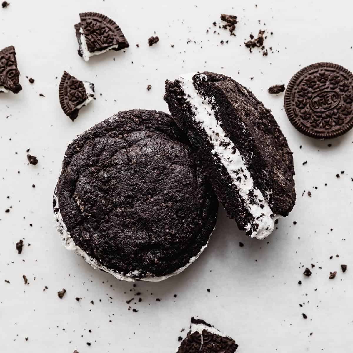 A copycat Crumbl Oreo cookie sandwich on a white background with Oreo crumbs surrounding the cookie.