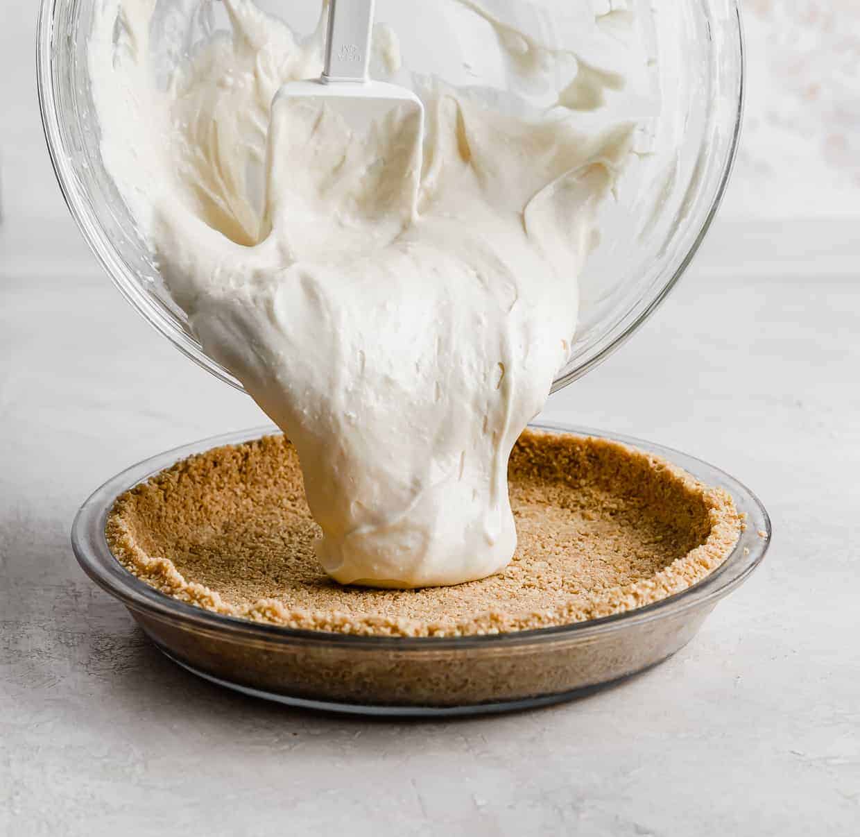 No-Bake Cheesecake filling being poured into a graham cracker crust.