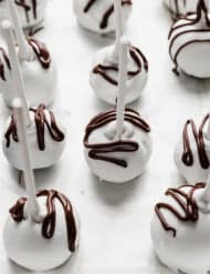 White chocolate covered Oreo Pops with brown chocolate drizzled overtop.