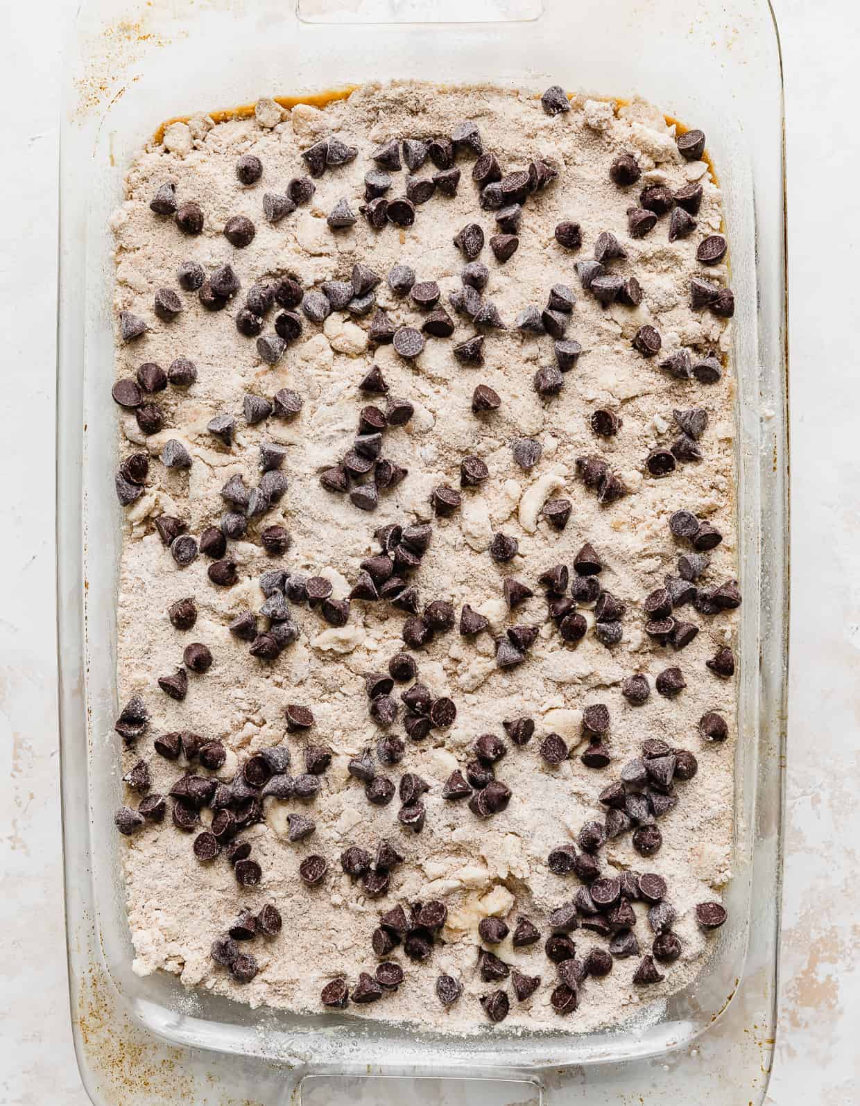 Pumpkin Chocolate Chip Coffee Cake topped with a sand colored crumble and chocolate chips in a baking dish.