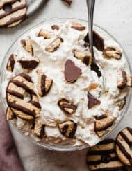 A glass bowl full of cookie salad topped with fudge stripe cookies.