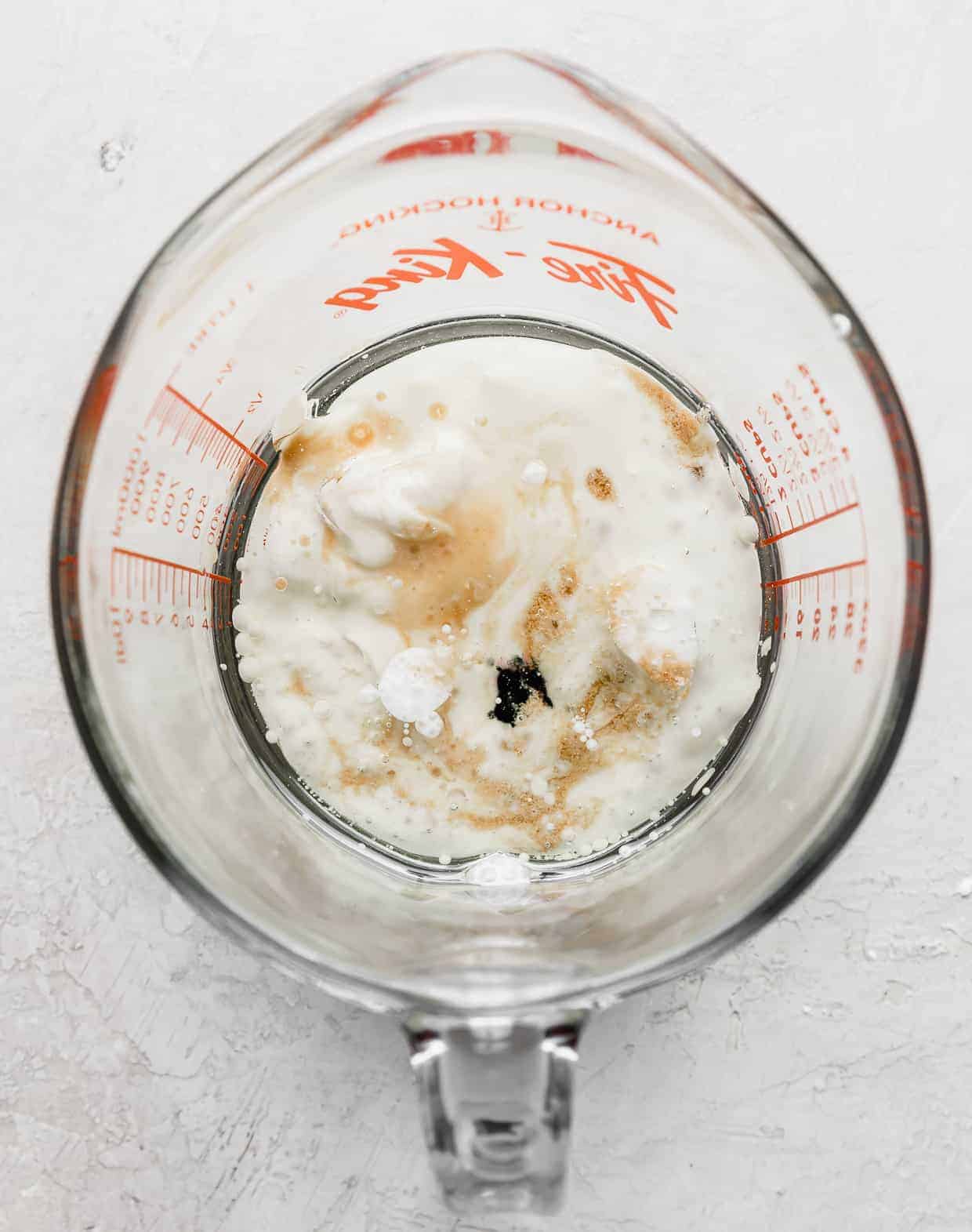 A glass measuring cup with wet ingredients used to make Black Velvet Cupcakes.