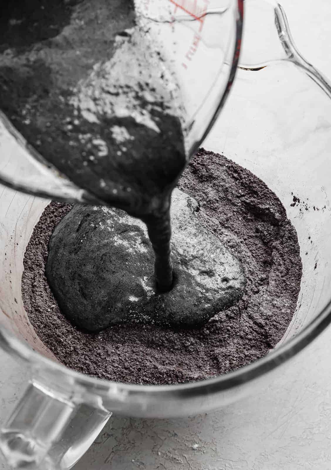 A black liquid mixture being poured into a glass bowl.