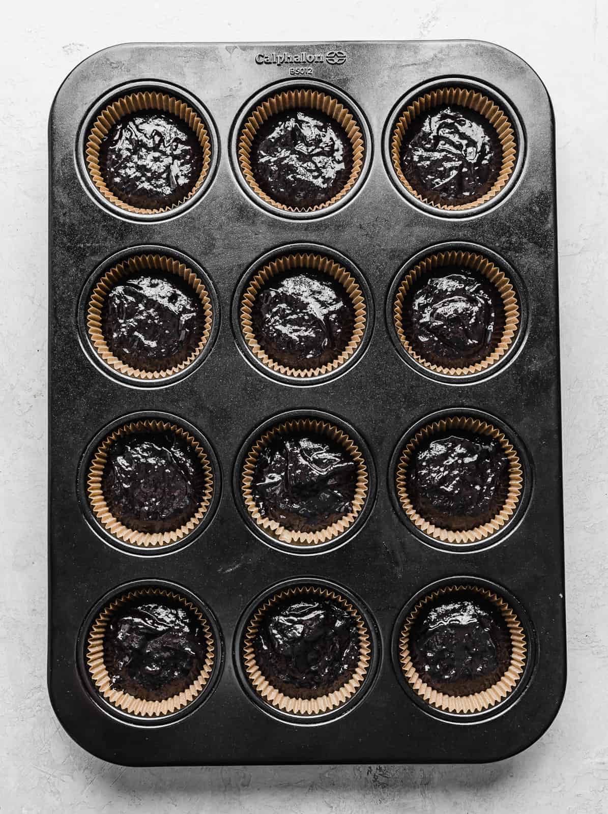 A cupcake pan with Black Velvet Cupcake batter in each compartment.