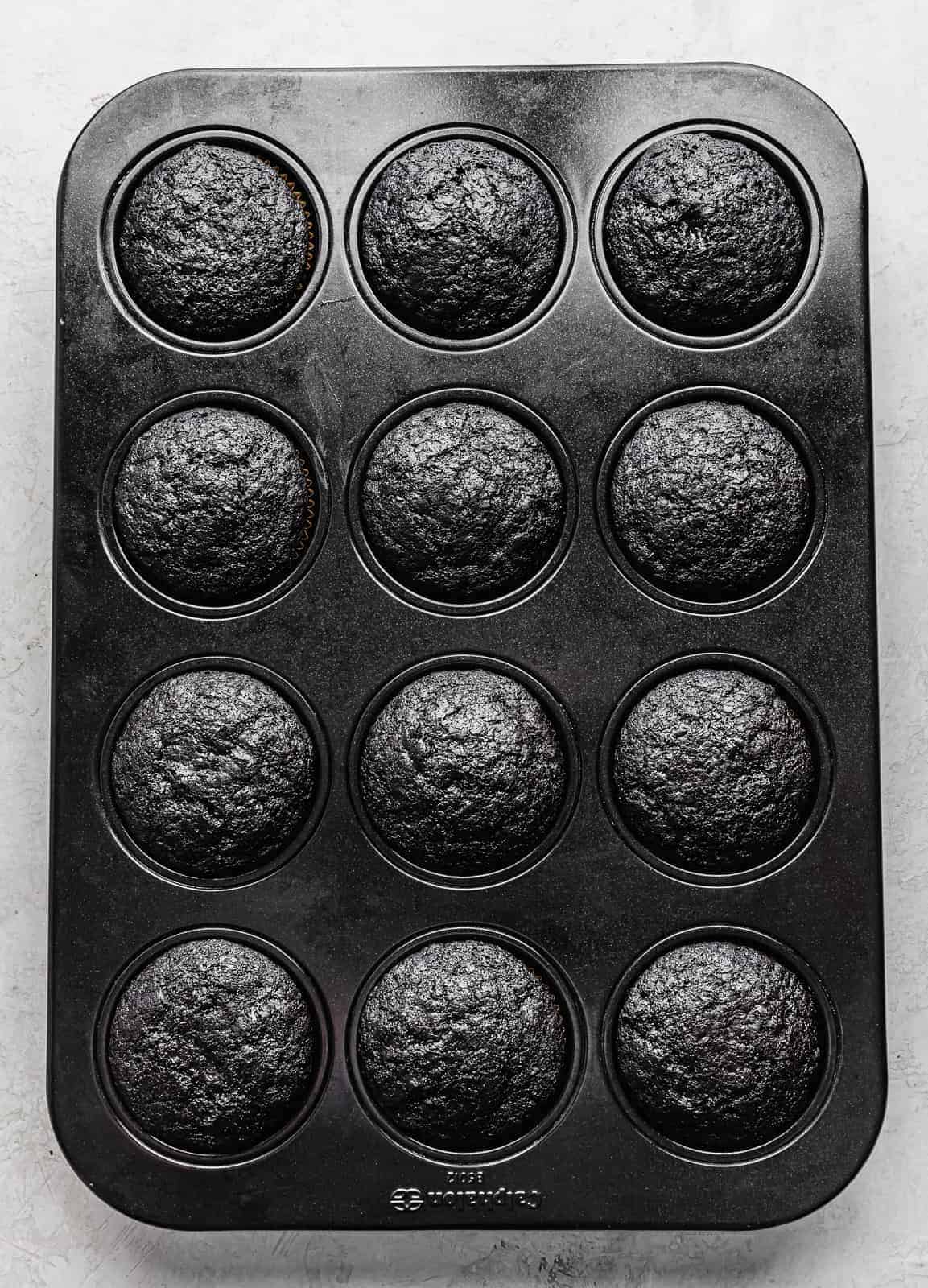Baked Black Velvet Cupcakes in a 12 compartment cupcake pan.