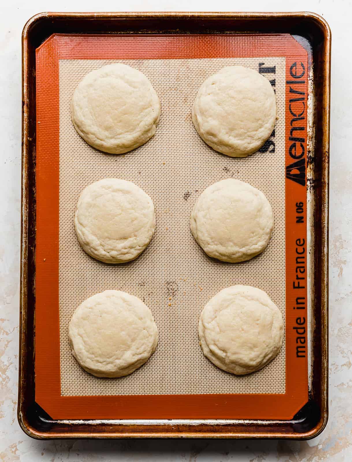 Six baked sugar cookies on a baking sheet.