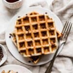 Chocolate Chip Waffles on a white plate with a fork to the right of the plate.