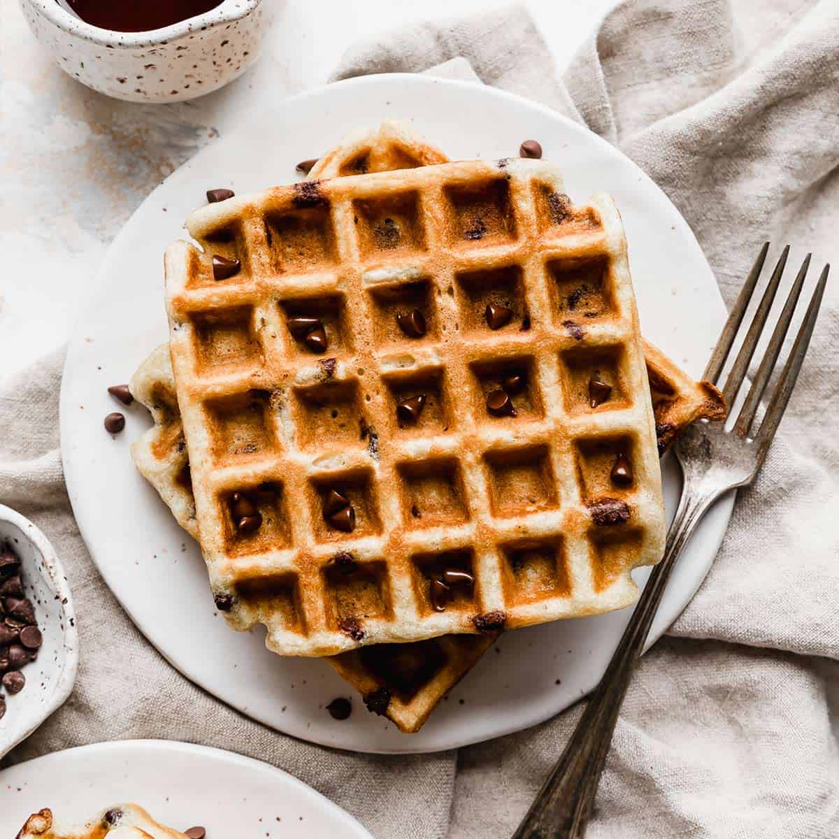 Chocolate Chip Waffles on a white plate with a fork to the right of the plate.