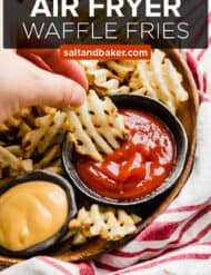 A hand dipping a waffle fry into ketchup.