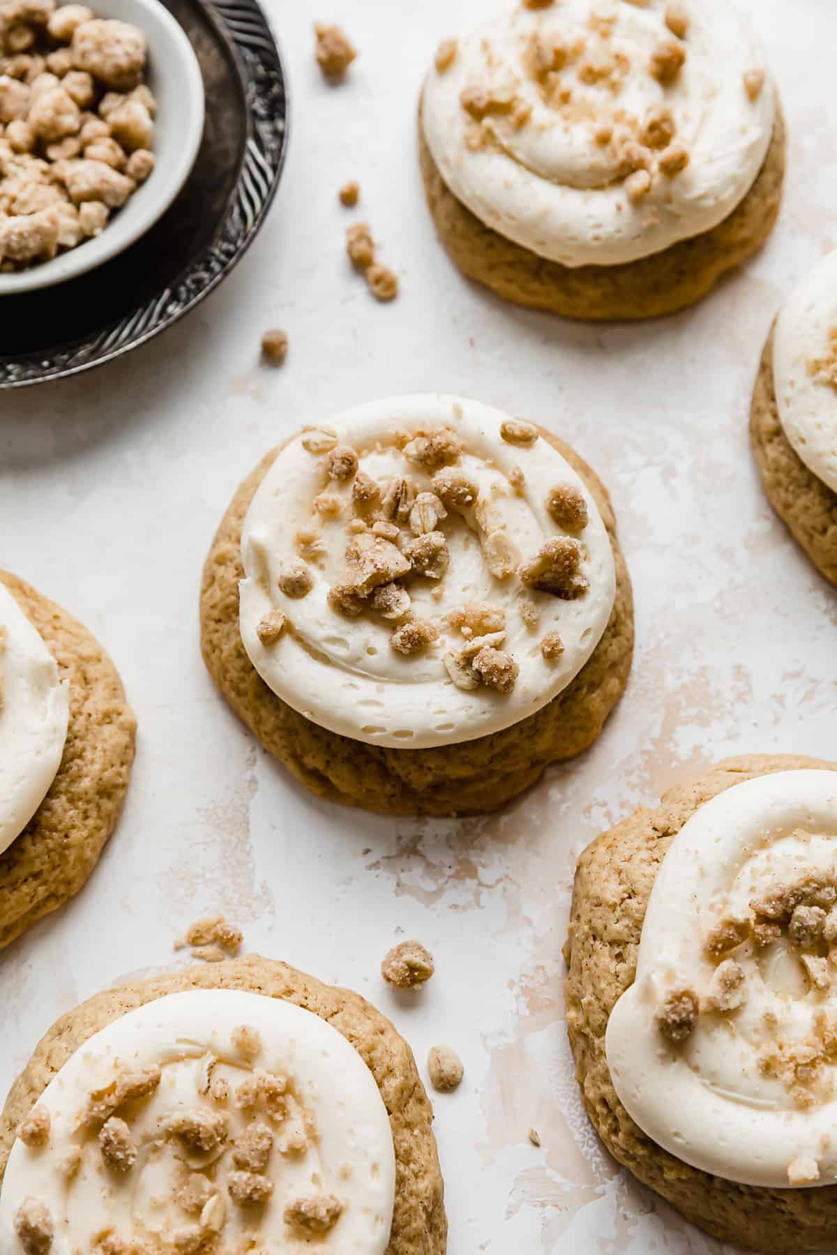 A caramel apple cookie topped with a homemade streusel topping on a textured cream background.